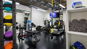 A gym with various exercise equipment, a water dispenser, and a television on the wall.