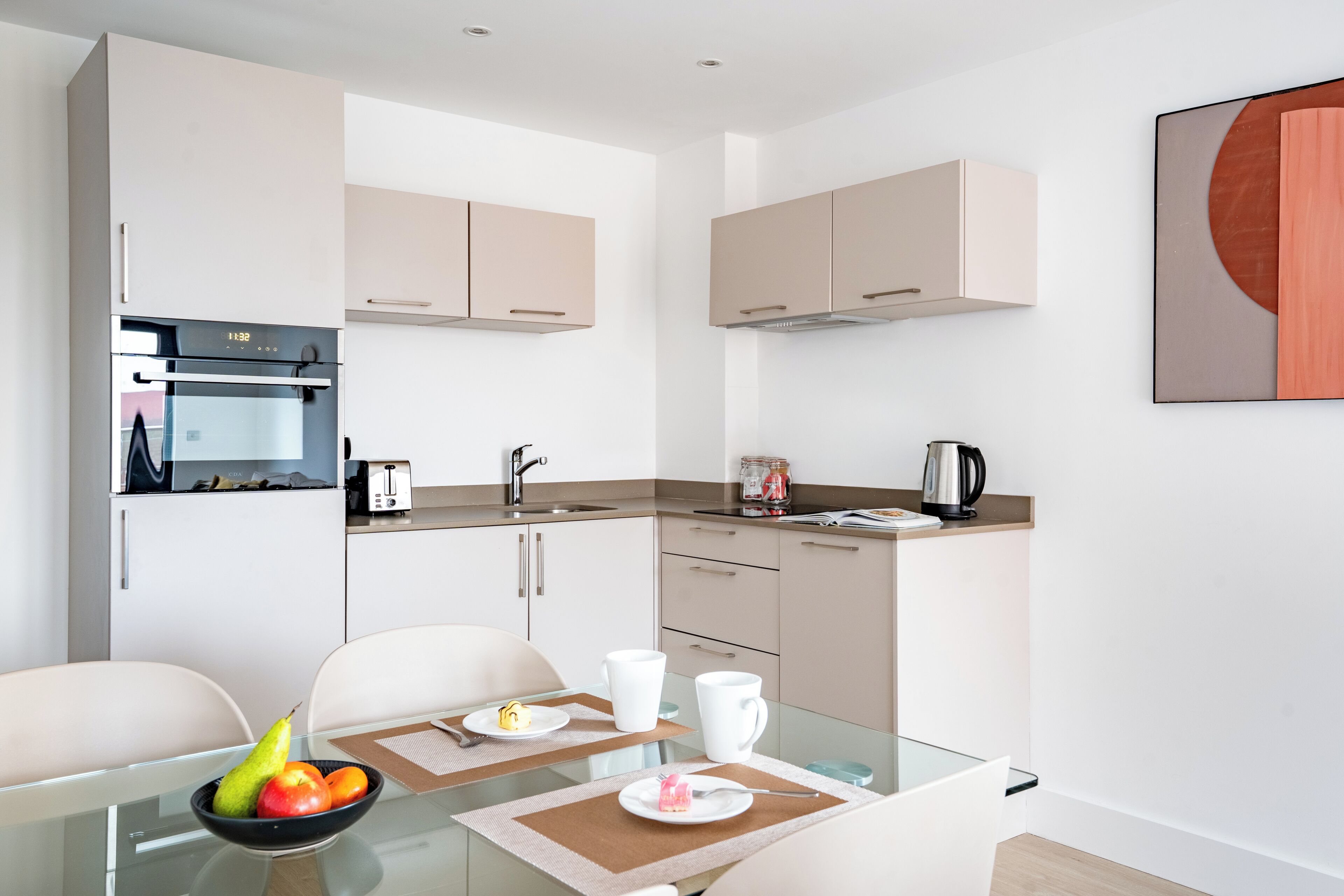 A modern kitchen with white cabinets, a built-in oven, and a coffee maker.