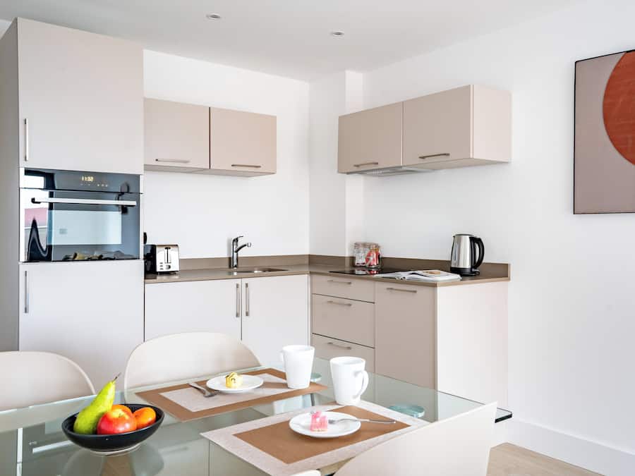 A modern kitchen with white cabinets, a built-in oven, and a coffee maker.