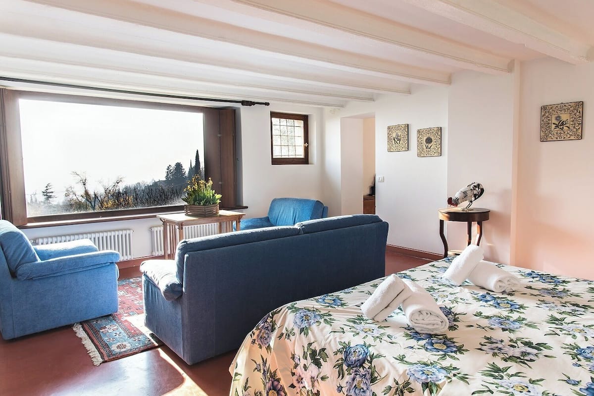 Ein Schlafzimmer mit einem Bett, zwei Sofas, einem kleinen Tisch und einem Fenster mit Blick.