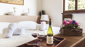 Una cama bien hecha con toallas enrolladas, dos copas de vino tinto y una botella de vino Amarone sobre una bandeja.