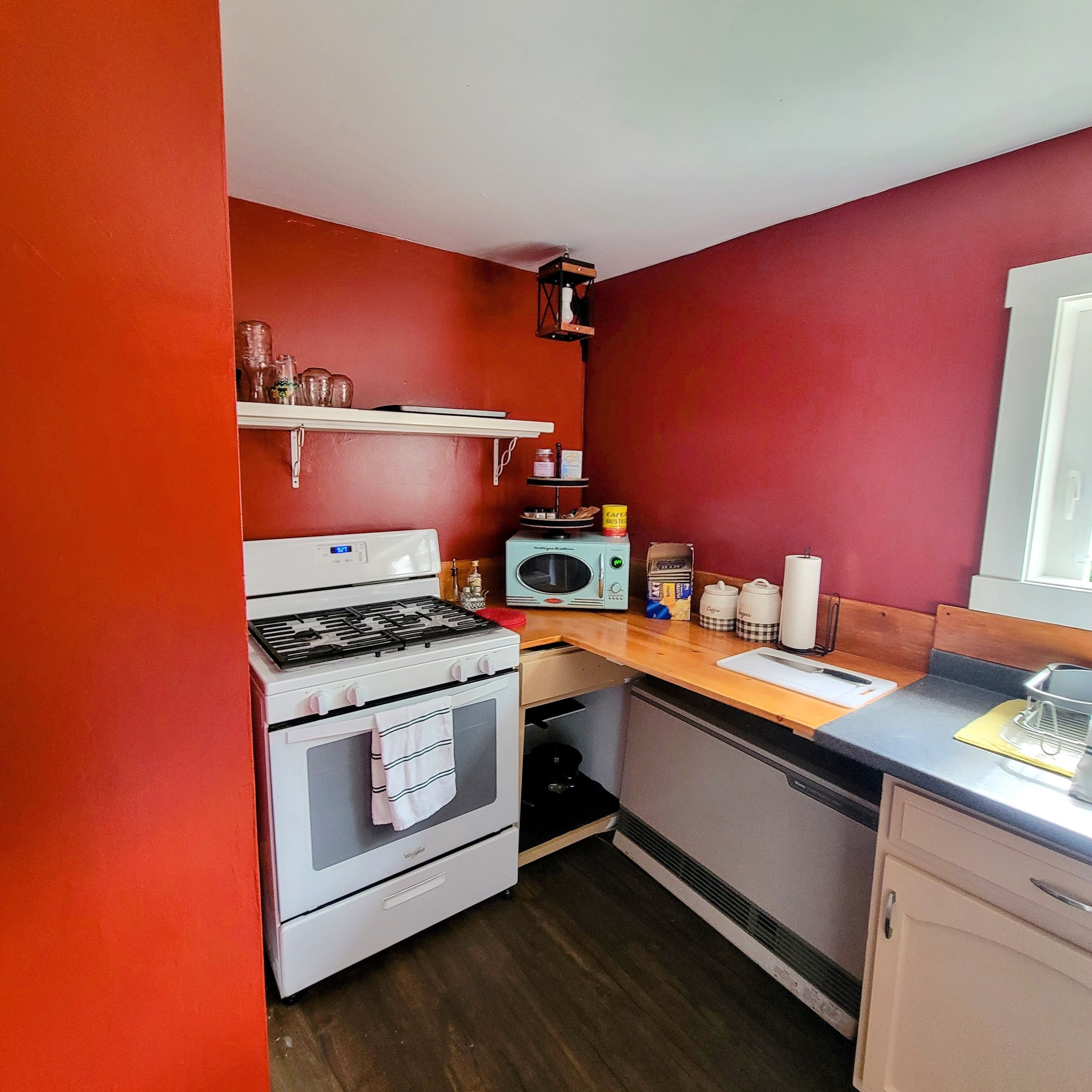 Une cuisine de taille réduite équipée d’une cuisinière à gaz, d’un four, d’un four à micro-ondes et d’un plan de travail en bois.