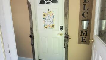 A white door with a 'Live Simply' sign, a 'Welcome' sign, and a doormat with 'Spring has sprung' text.