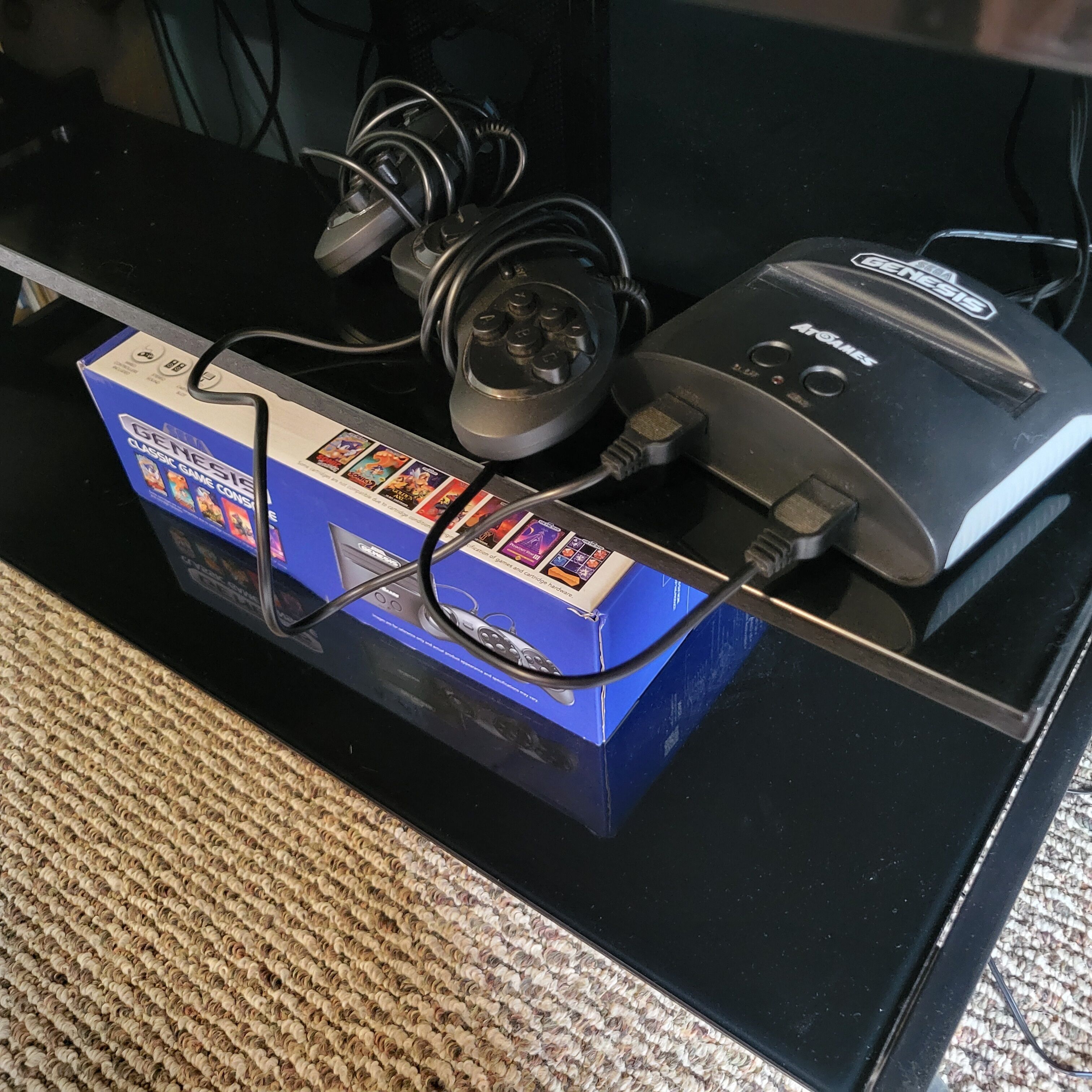 A black table with a blue box labeled "GENESIS" and a black device with a cord plugged into it.