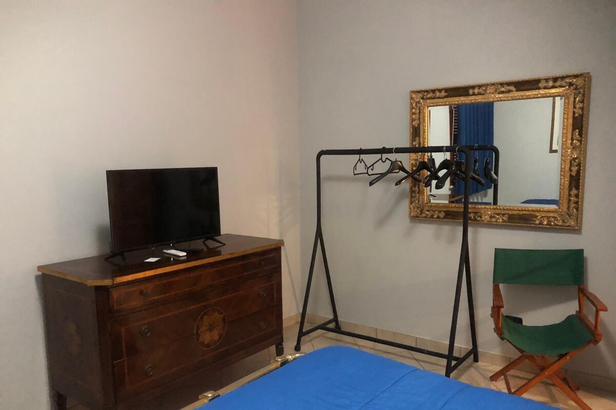 A room with a bed, a dresser, a television, a mirror, and a chair.