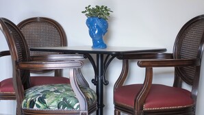 A dining table with four chairs, each with a red cushion. A blue vase with a plant is on the table. - HOTEL SERENA (Naples)