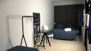 A hotel room with a bed, a chair, a small table, and a mirror. - HOTEL SERENA (Naples)