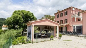 A two-story building with a covered patio area, outdoor seating, and a poolside area with lounge chairs. - Villa Oliva Vilea in Sveta Marina  - Haus für 8 Personen (Labin)