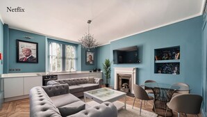 A modern living room with a sectional sofa, a glass coffee table, and a fireplace. - The Governance Apartments (Windermere)