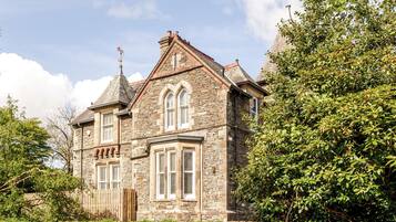 A stone building with a gabled roof, multiple windows, and a wooden fence.