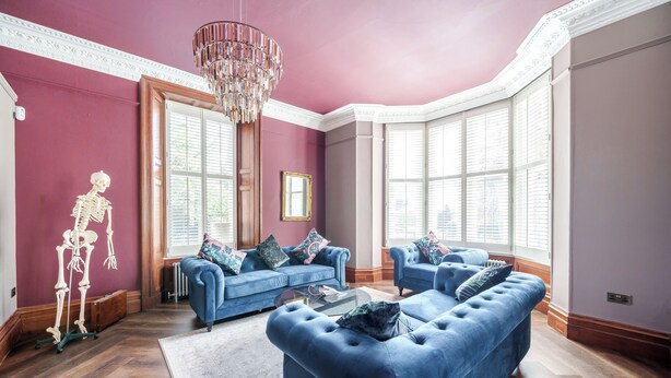 A living room with two blue sofas, a chandelier, and a skeleton decoration. - The Governance Apartments (Windermere)