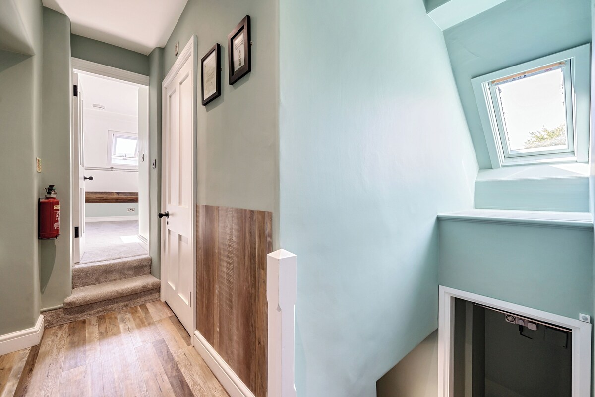 A hallway with a wooden floor, a white door, and a window with a view of the outdoors.