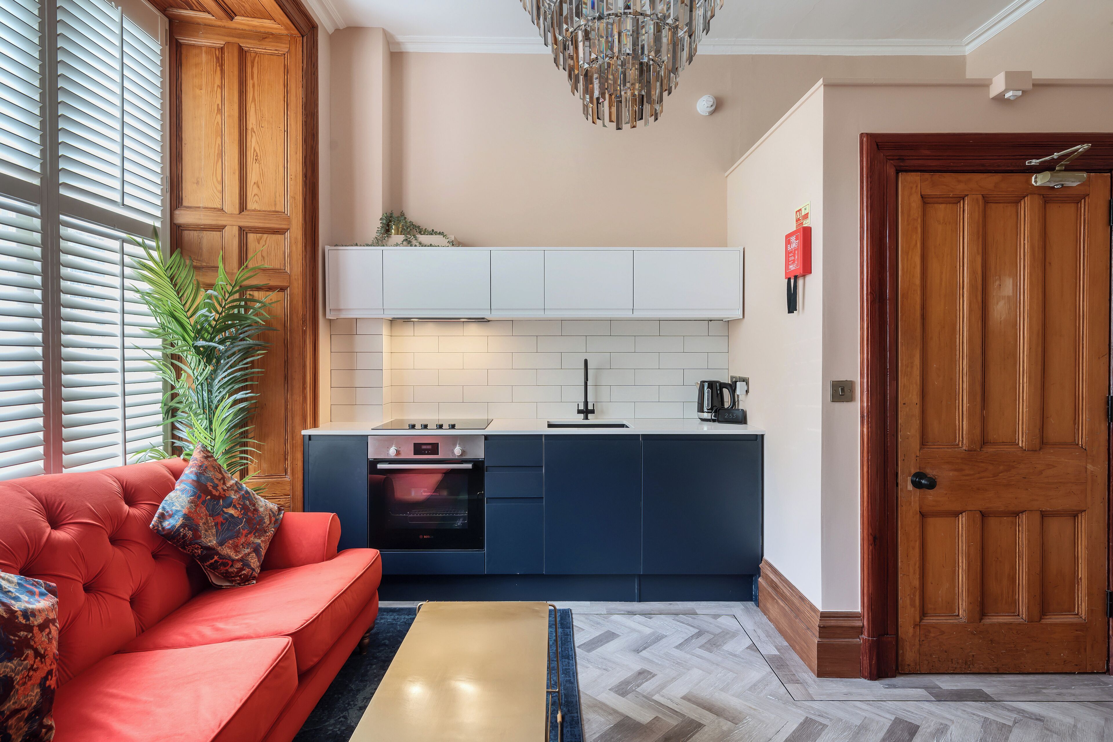 Una cocina compacta con horno integrado, armarios blancos y una puerta de madera.