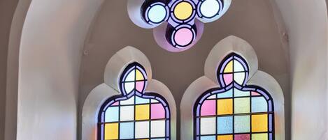 Una ventana de vitral con un diseño simétrico, que presenta un motivo circular central y dos figuras simétricas debajo.