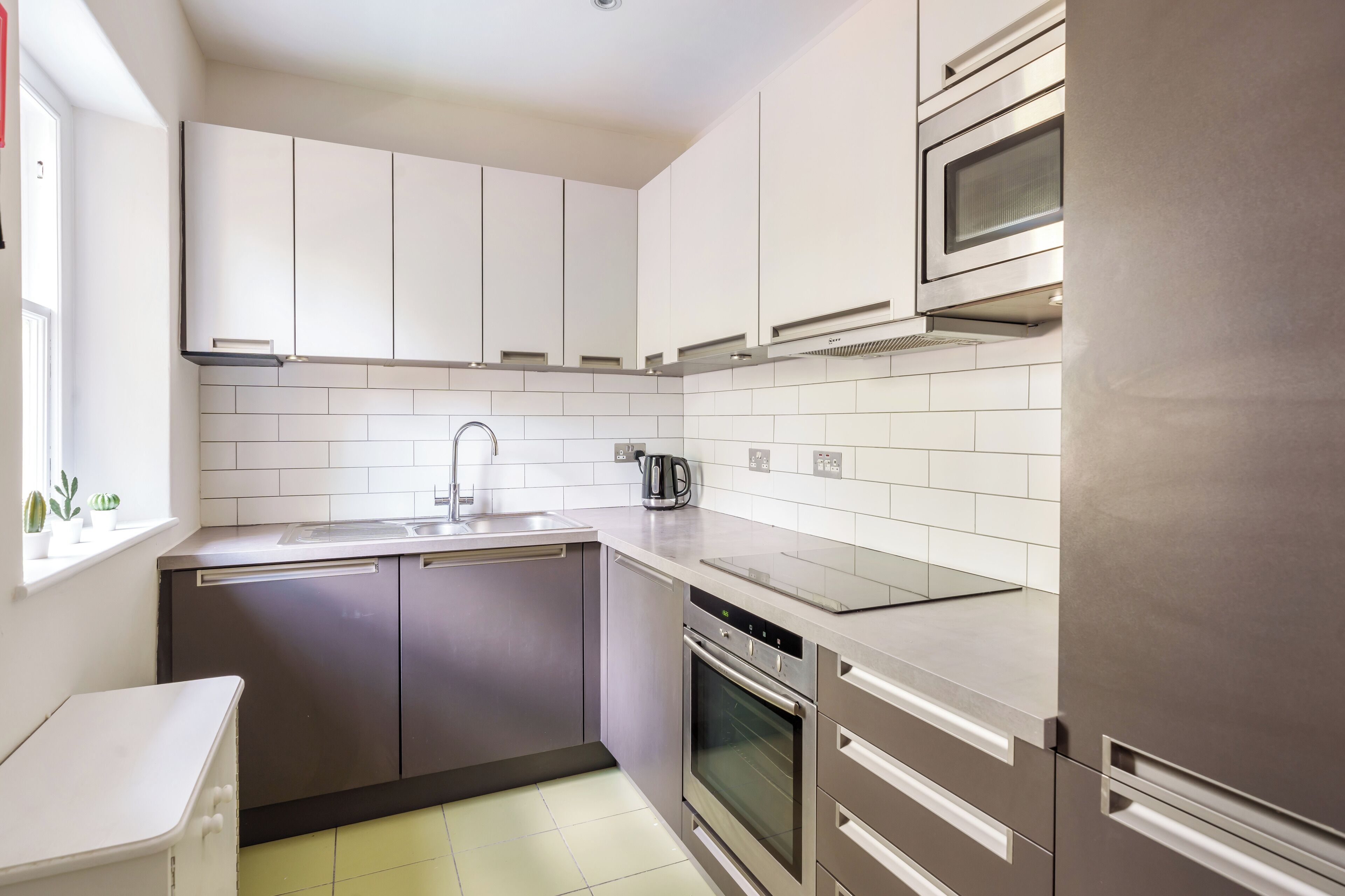 A modern kitchen with stainless steel appliances, white cabinets, and a tiled backsplash.