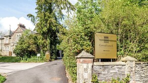 A sign for 'The Governance Boutique Hotel' with a stone wall and greenery. - The Governance Apartments (Windermere)