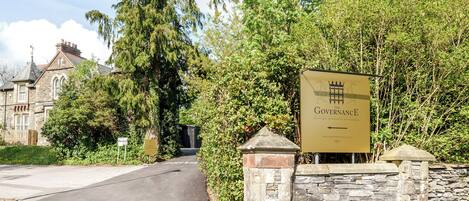 A sign for 'The Governance Boutique Hotel' with a stone wall and greenery.