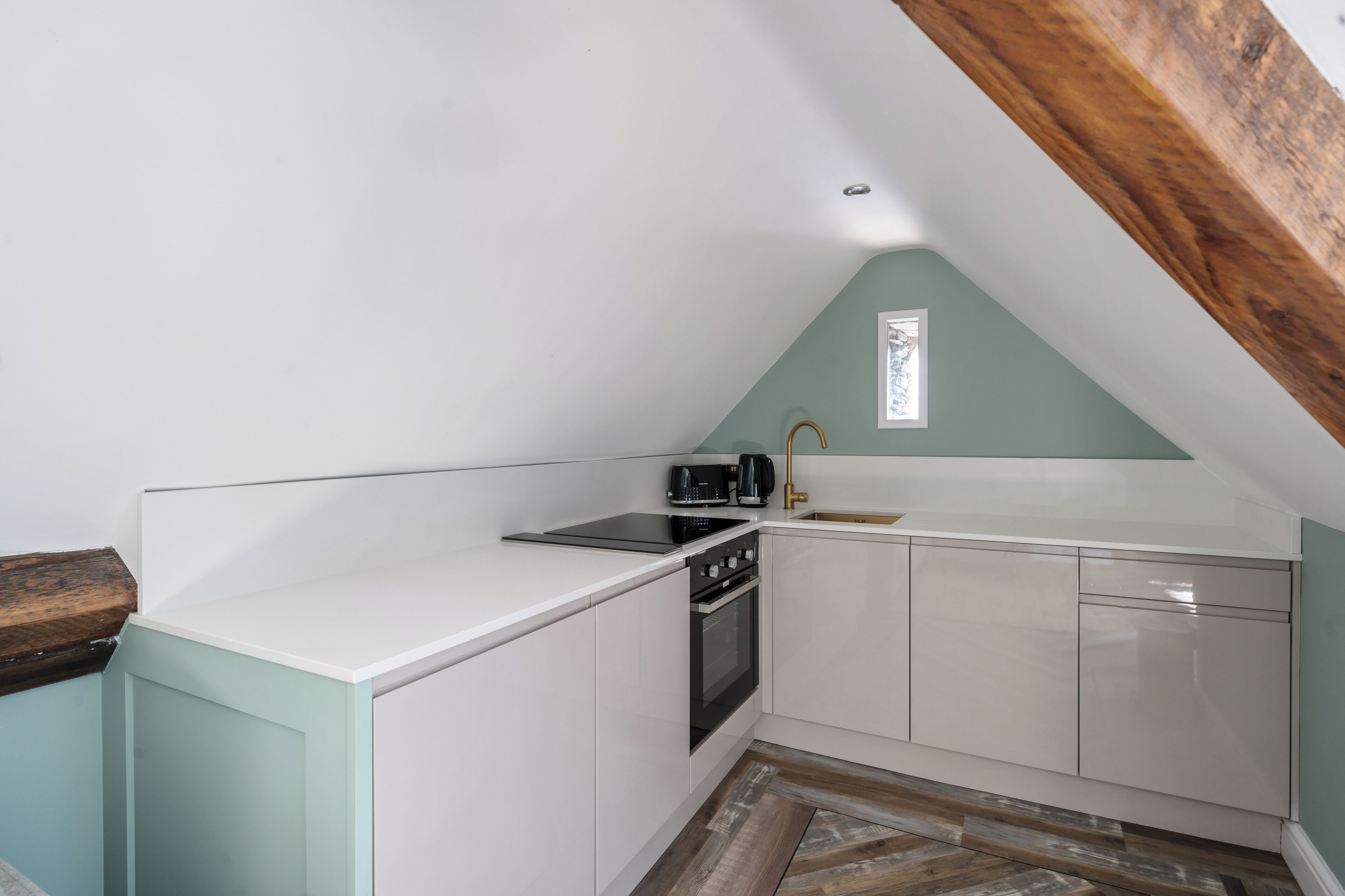 A kitchen with white cabinets, a black stove, and a wooden ceiling.