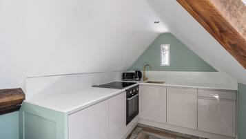 A kitchen with white cabinets, a black stove, and a wooden ceiling.