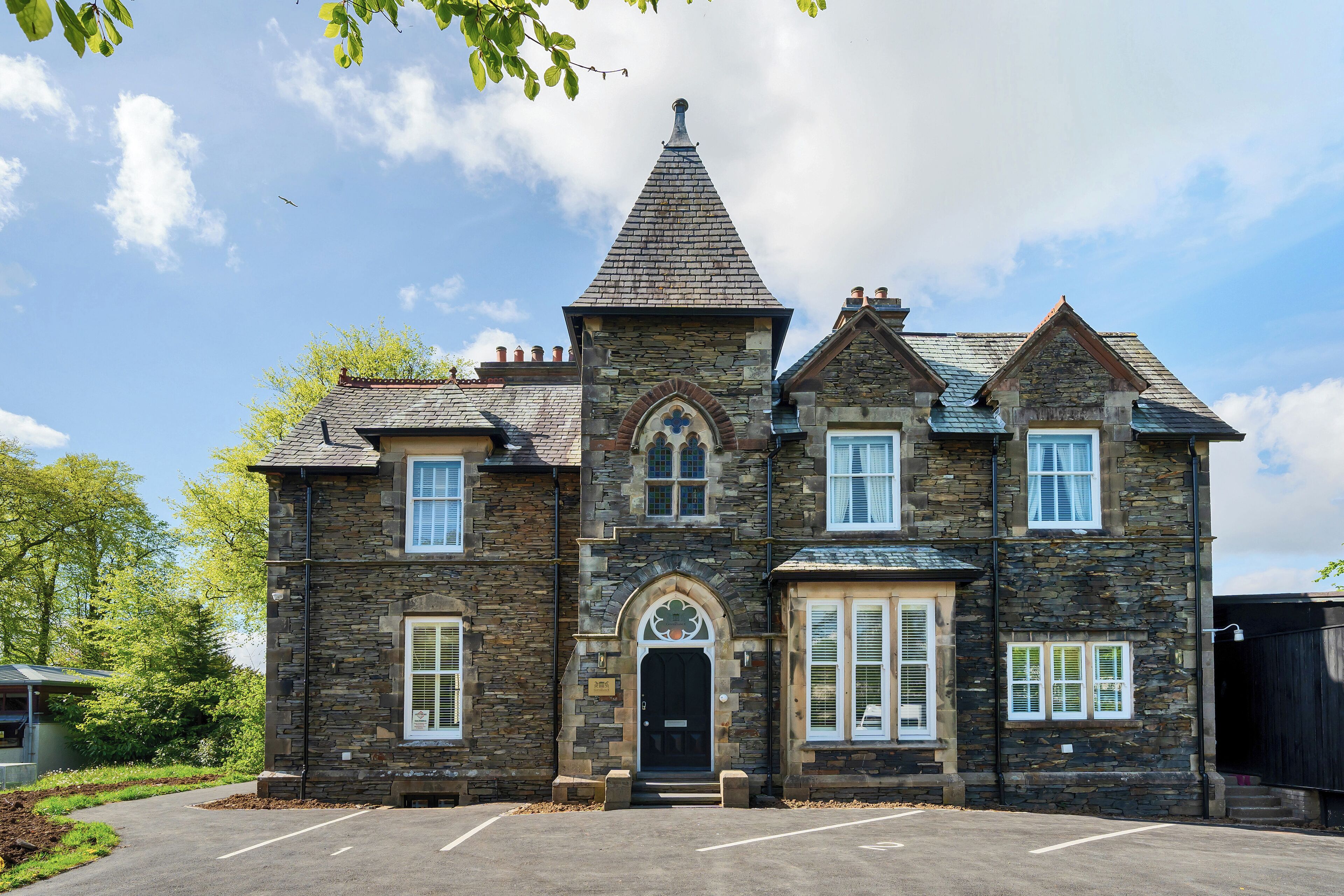 A stone building with a central tower, multiple windows, and a black door.
