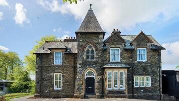 A stone building with a central tower, multiple windows, and a black door.