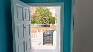 A doorway leading to an outdoor area with a white door, a woven ceiling light fixture, and a small rug on the floor. - House with 2 terraces and sea view. 2 Bedrooms, 500m from the Beach. (Puerto de Mazarrón)