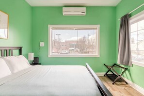 A room with a bed, a window, an air conditioner, and a nightstand with a lamp. - Private Portland Group Getaway - Sleeps 12 (Portland)