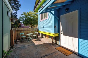A blue house with a white garage door, a small patio with a table and chairs, and a wooden fence in the background. - Private Portland Group Getaway - Sleeps 12 (Portland)
