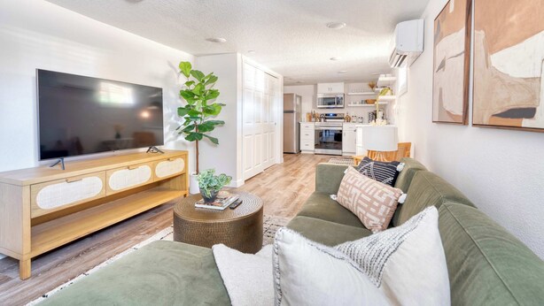 A modern living room with a flat-screen TV, a wooden console, a green sofa, and a round coffee table. - Vibrant Portland Getaway - Chic Flat (Portland)