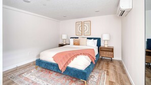 A bedroom with a blue bed, white walls, and a patterned rug. - Vibrant Portland Getaway - Chic Flat (Portland)