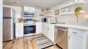 A modern kitchen with white cabinetry, stainless steel appliances, and built-in shelves. - Vibrant Portland Getaway - Chic Flat (Portland)