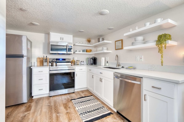A modern kitchen with white cabinetry, stainless steel appliances, and built-in shelves. - Vibrant Portland Getaway - Chic Flat (Portland)