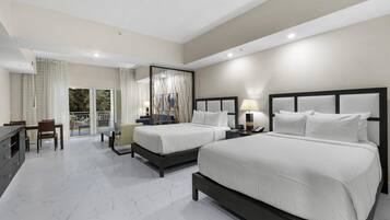 A hotel room with two beds, a dining area, and a balcony with curtains.