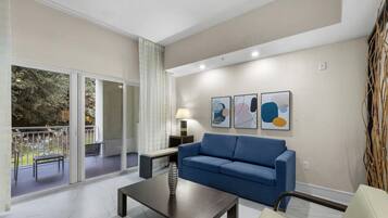 A modern living room with a blue sofa, a coffee table, and abstract art on the wall.