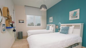 A bedroom with two beds, a window, and teal walls. - Gorgeous 2BR Marina View Retreat (Río Hato)