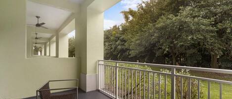 A balcony with a metal railing, a bench, and a ceiling fan.