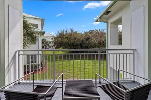 A balcony with metal railings, a grassy lawn, and a building with a green roof in the background. - Studio Sleeps 5, Kitchen, Lanai, Pool, Parking (Miami)