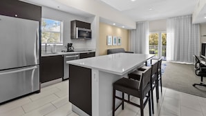 A modern kitchen with a central island, stainless steel appliances, and a dining area with a view of the outdoors. - Studio Sleeps 5, Kitchen, Lanai, Pool, Parking (Miami)