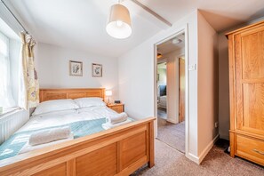 A bedroom with a wooden bed, a nightstand, a lamp, and a wardrobe. - Beautiful Riverside Cottage with Large Garden, 2BR (Hampshire)