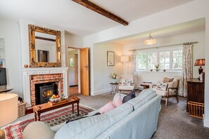 A cozy living room with a fireplace, a sofa, a coffee table, and a large mirror.