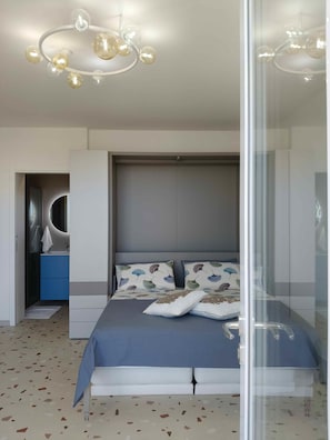 Un dormitorio moderno con cama, separador de vidrio, un armario azul y una lámpara de techo original.