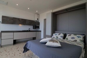 A modern bedroom with a bed, pillows, a nightstand, and a built-in wardrobe.