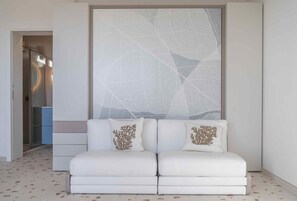 A modern interior with a white sofa set, a large abstract wall art piece, and a patterned floor.