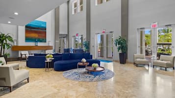 A spacious lobby with a blue sofa, a round coffee table, and a large painting on the wall.