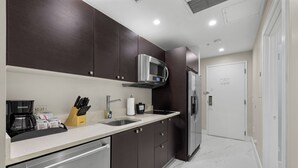 A modern kitchen with dark cabinets, stainless steel appliances, and a white countertop. - Heart of Downtown Doral – Resort Style Studio (Miami)