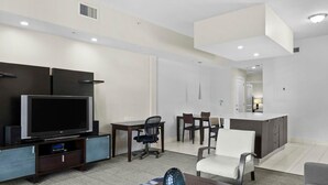 A modern living room with a flat-screen TV, a dining area with a table and chairs, and a kitchen with a white countertop. - Spacious 1,070 Sq Ft Studio with Kitchen (Miami)