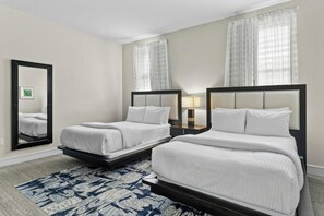Une chambre d’hôtel avec deux lits, un grand miroir et un tapis à motifs.