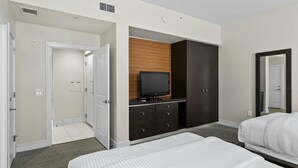 A hotel room with a bed, a TV on a wooden cabinet, a wardrobe, and a mirror. - Spacious 1,070 Sq Ft Studio with Kitchen (Miami)