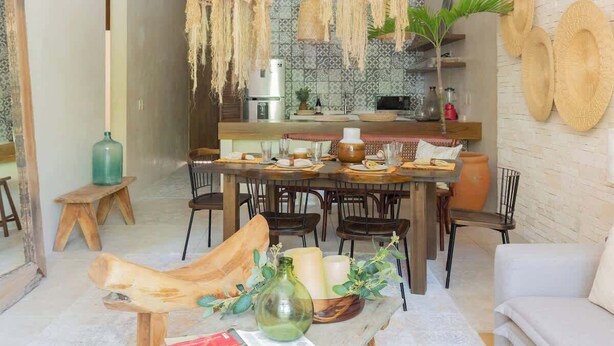 Un salon moderne avec une table basse en bois, un canapé et un coin repas, avec une cuisine en arrière-plan.