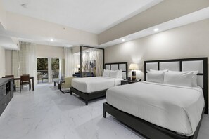 A hotel room with two beds, a dining area, and a balcony with curtains.